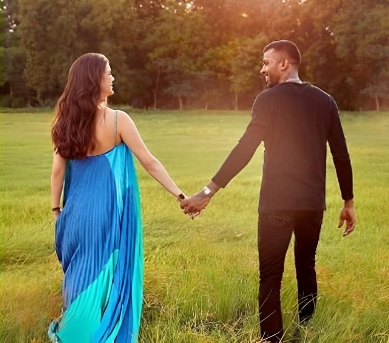 Their love and anticipation for their upcoming bundle of joy shine through, as they stand hand in hand in a field, exuding sheer happiness